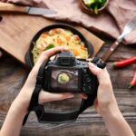 Junge Frau fotografiert Essen auf Holztisch